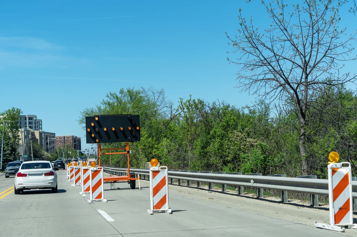 Traffic control with cones and electronic arrow sign during a lane closure and road maintenance.