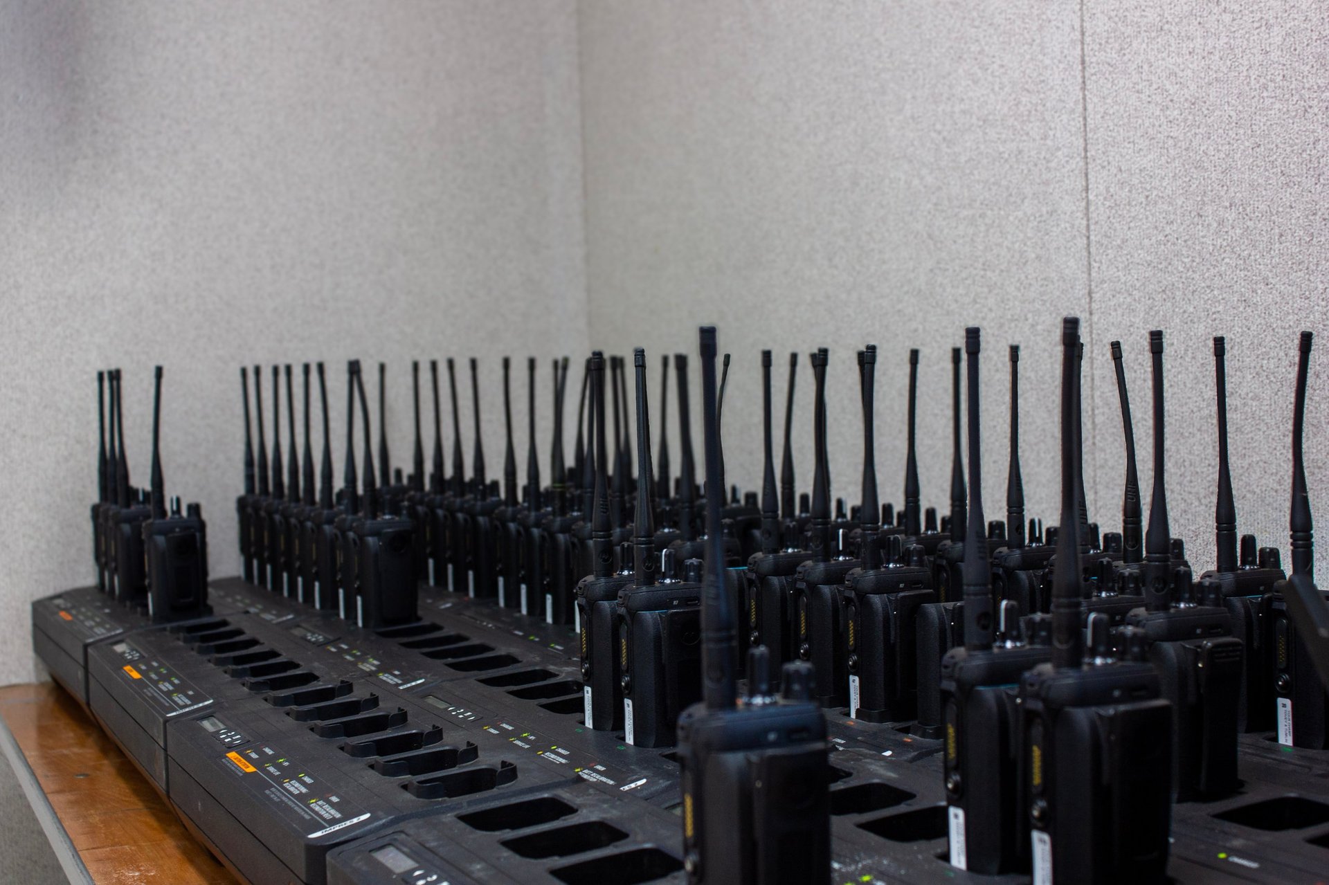 Array of black cell phone signal jammers with antennas arranged in rows on a table
