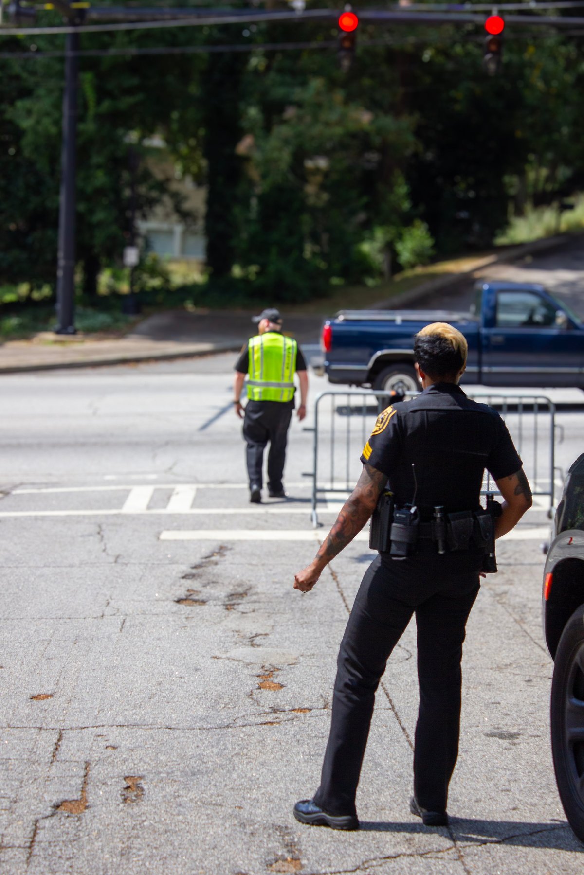 Police officer directing traffic at an intersection with a construction worker and red traffic lights visible